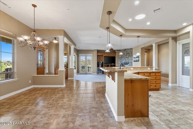 1183 Northridge Dr, Prescott, AZ 86301 - kitchen with open floor plan, a chandelier, a stone fireplace, light stone counters, and pendant lighting