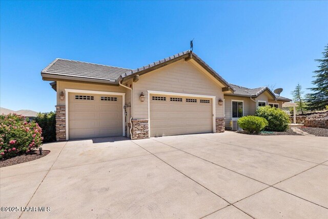 1183 Northridge Dr, Prescott, AZ 86301 - view of front of property featuring stone siding, an attached garage, driveway, and a tiled roof