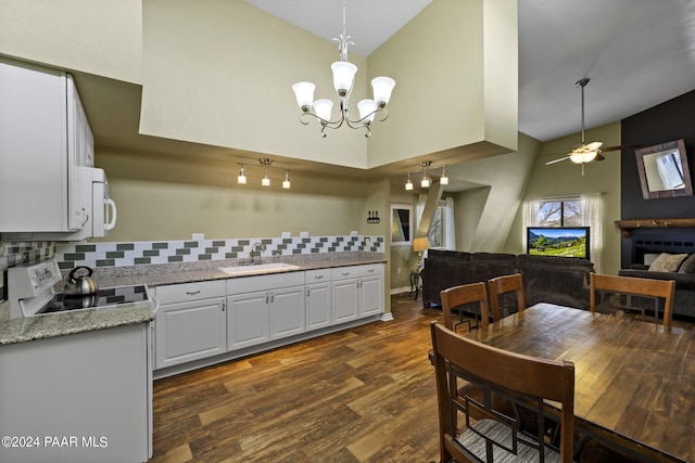 kitchen with dark wood-type flooring, high vaulted ceiling, range, sink, and white cabinetry