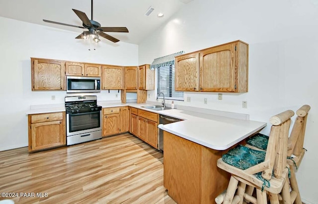 kitchen with kitchen peninsula, light wood-type flooring, stainless steel appliances, and sink