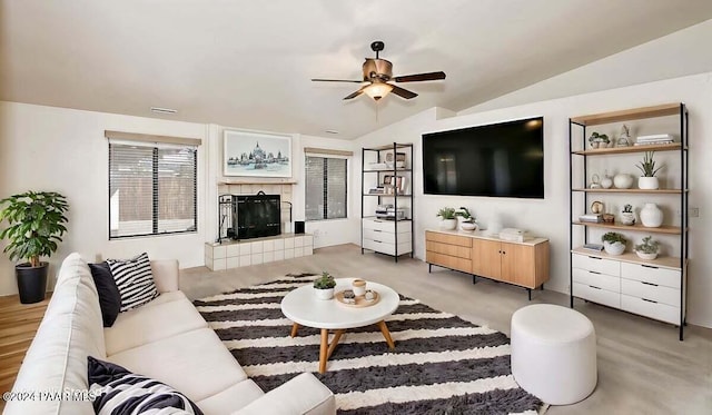 living room featuring ceiling fan, light hardwood / wood-style flooring, a fireplace, and vaulted ceiling