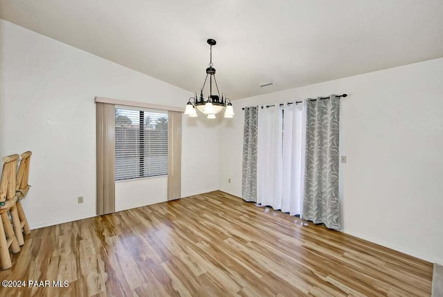 unfurnished dining area featuring hardwood / wood-style floors, lofted ceiling, and a notable chandelier