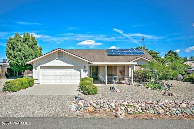 ranch-style home featuring covered porch, a garage, and solar panels