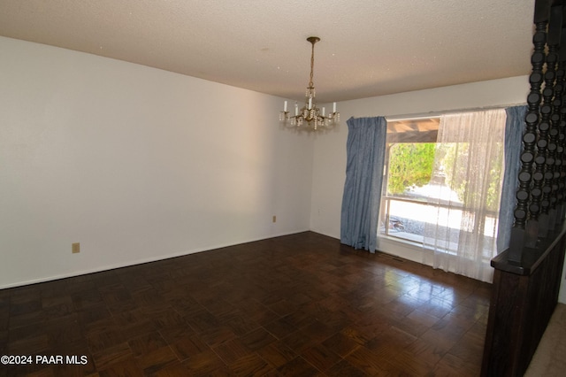 empty room with a notable chandelier and a textured ceiling