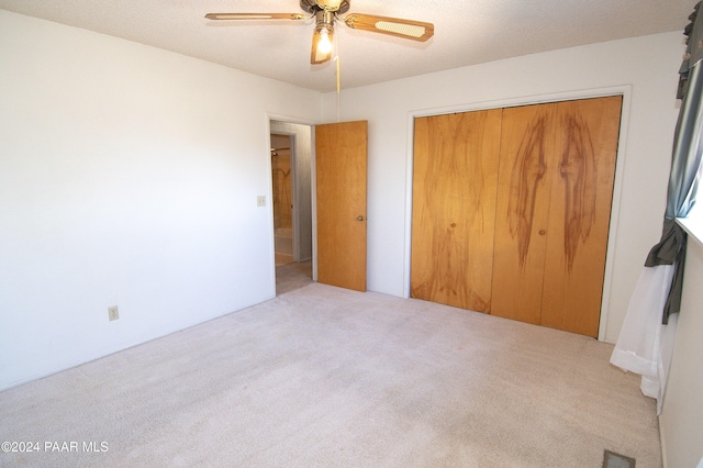 unfurnished bedroom featuring ceiling fan, a closet, and light colored carpet