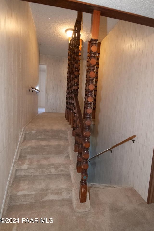 staircase with carpet and a textured ceiling