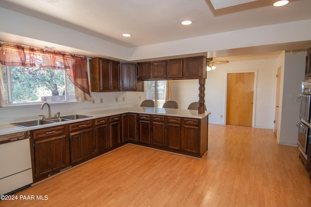 kitchen featuring dishwasher, kitchen peninsula, sink, and light hardwood / wood-style flooring