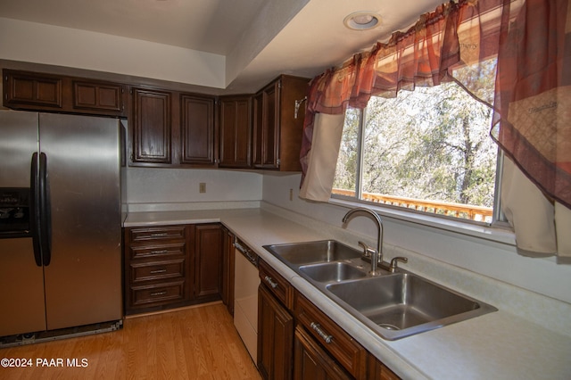 kitchen featuring stainless steel refrigerator with ice dispenser, dishwashing machine, dark brown cabinets, sink, and light hardwood / wood-style floors