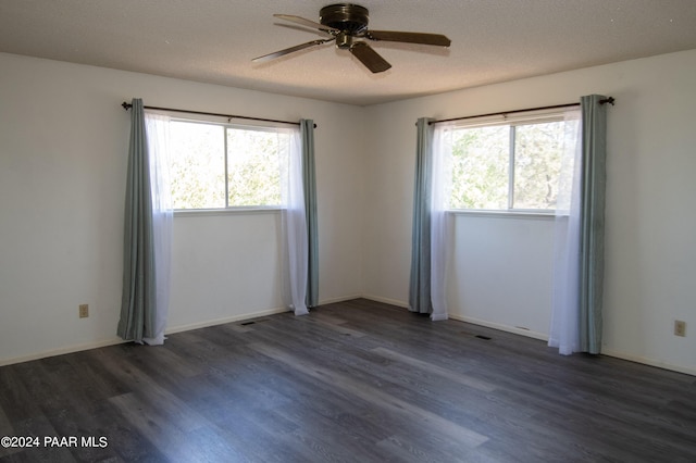 unfurnished room featuring ceiling fan, dark wood-type flooring, and a wealth of natural light