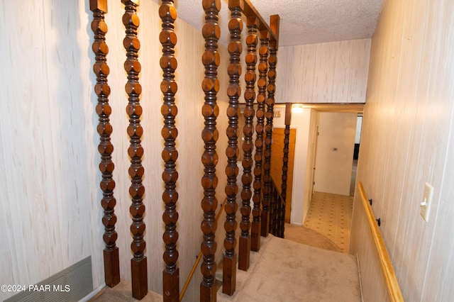 hall featuring light carpet and a textured ceiling