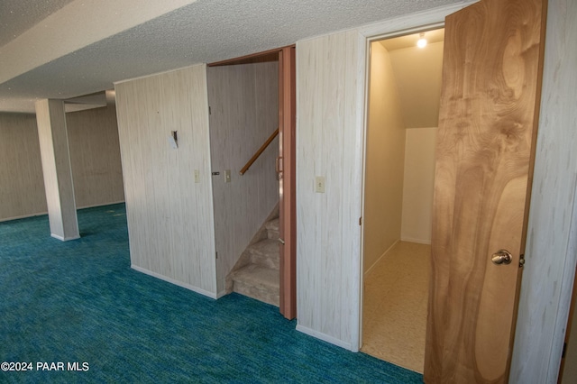 basement with dark colored carpet, a textured ceiling, and wooden walls