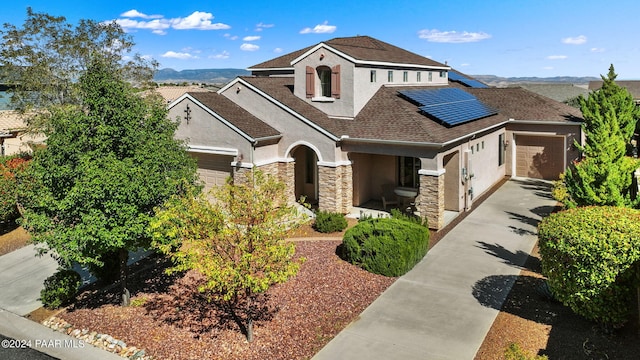 view of front of home featuring solar panels, a garage, and a mountain view