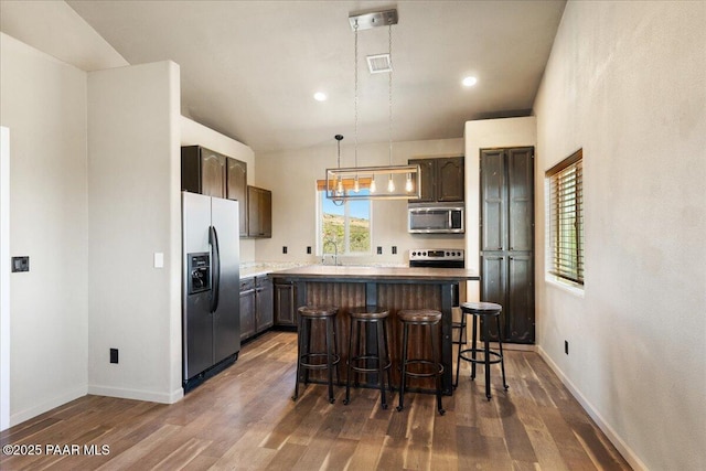 17940 E Native Dancer Ln, Dewey-Humboldt, AZ 86327 - kitchen with stainless steel appliances, dark wood finished floors, a breakfast bar, a center island, and decorative light fixtures