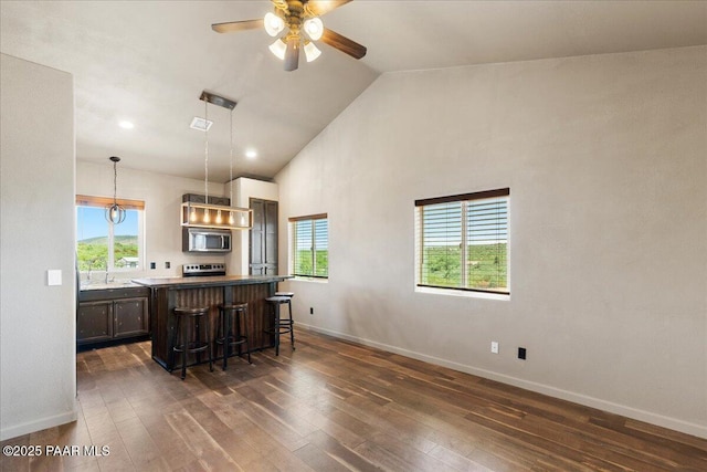 17940 E Native Dancer Ln, Dewey-Humboldt, AZ 86327 - kitchen with stainless steel microwave, a kitchen bar, a center island, dark wood-type flooring, and ceiling fan