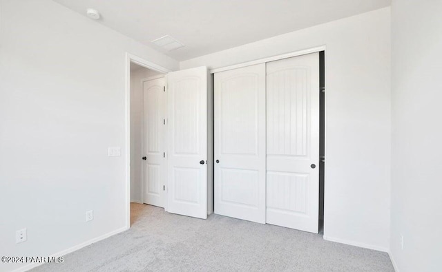 unfurnished bedroom featuring light carpet and a closet