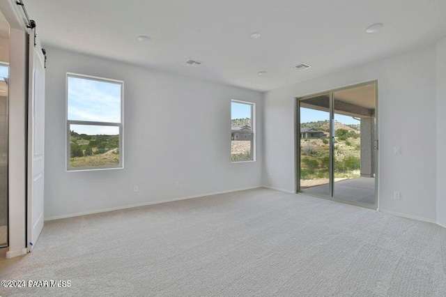 empty room with a barn door and light colored carpet