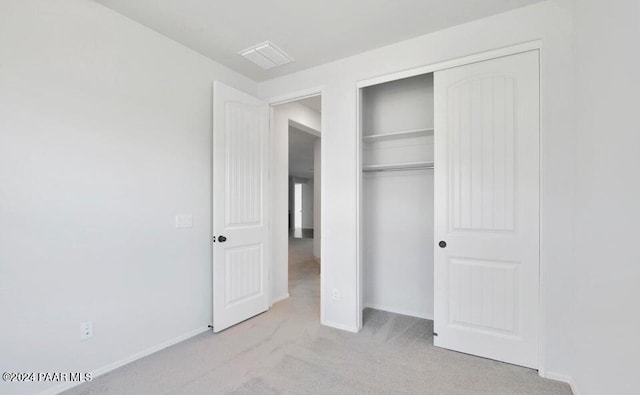 unfurnished bedroom featuring light carpet and a closet