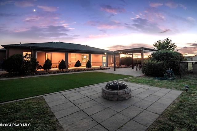 patio terrace at dusk featuring a fire pit and a lawn