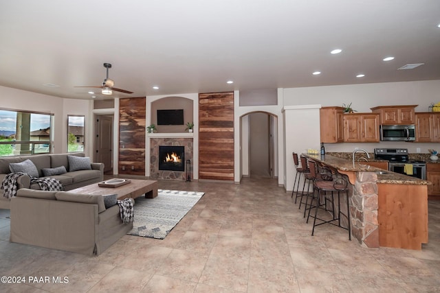 living room with a fireplace, ceiling fan, and sink