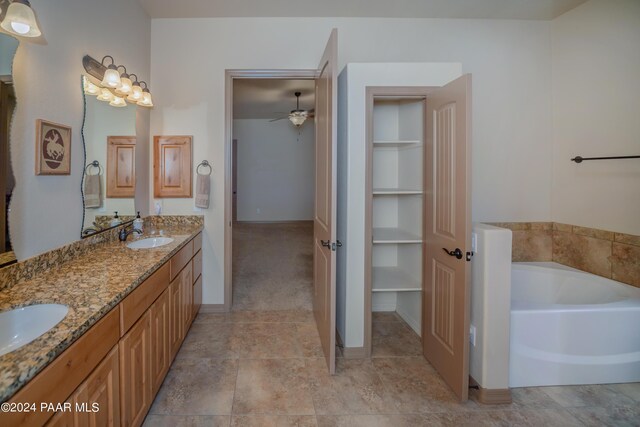 bathroom featuring ceiling fan, built in features, a tub, and vanity