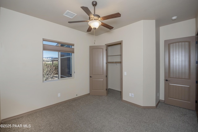 unfurnished bedroom with a walk in closet, ceiling fan, a closet, and light carpet