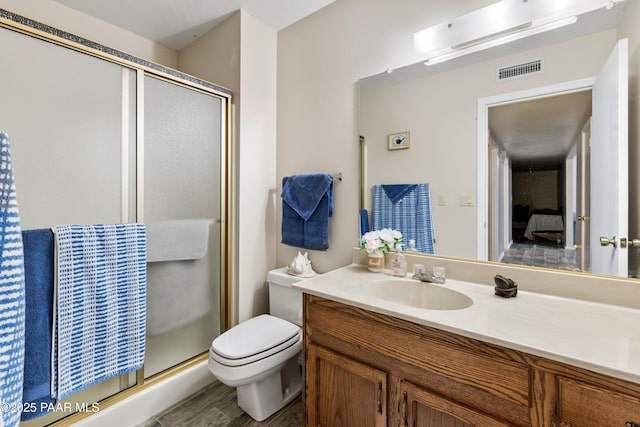 full bath featuring toilet, visible vents, wood finished floors, a shower stall, and vanity