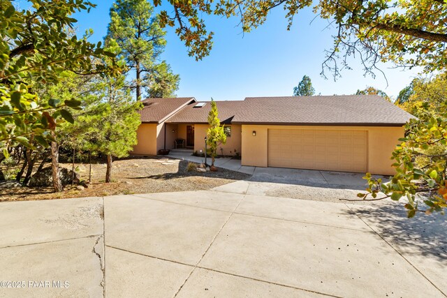 ranch-style home with an attached garage, driveway, stucco siding, and roof with shingles
