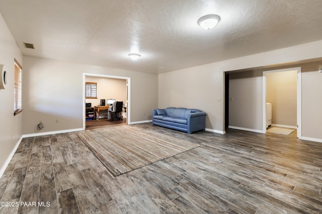 living area featuring visible vents, baseboards, and wood finished floors