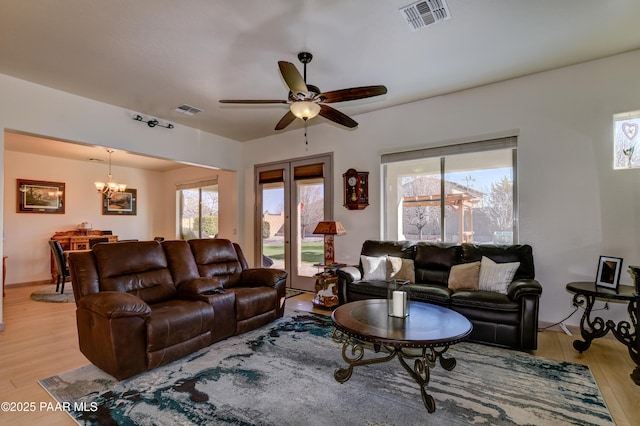 living room featuring ceiling fan with notable chandelier and light hardwood / wood-style floors