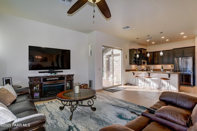 living room featuring ceiling fan, sink, and light hardwood / wood-style flooring