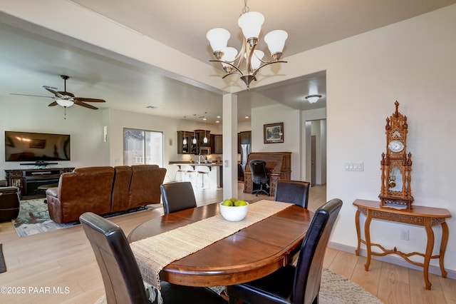 dining area with ceiling fan with notable chandelier and light wood-type flooring