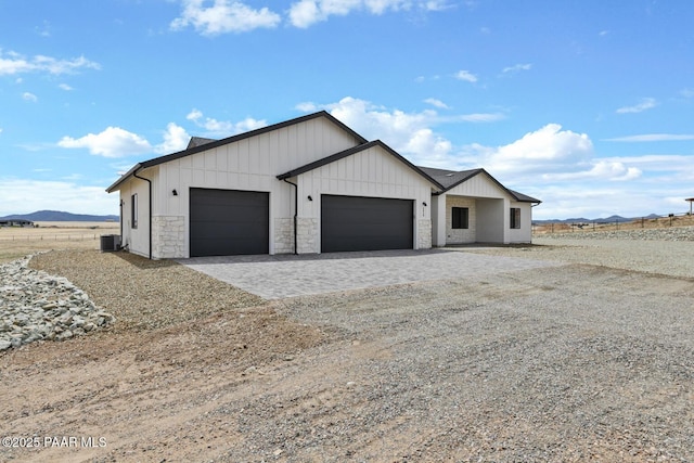 6829 E Sapphire Ln, Prescott Valley, AZ 86315 - view of front of home featuring an attached garage, decorative driveway, a mountain view, stone siding, and central air condition unit