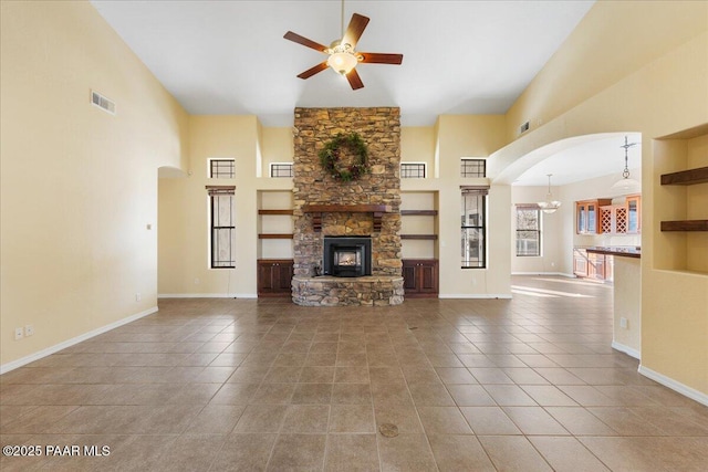 unfurnished living room featuring a towering ceiling, a fireplace, tile patterned floors, and ceiling fan