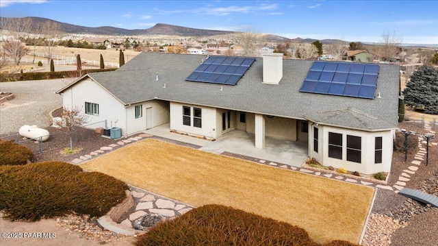 rear view of property featuring a patio, a mountain view, and solar panels