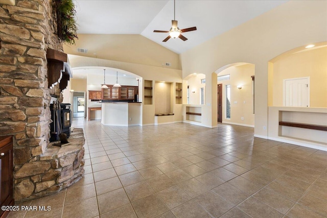 unfurnished living room with ceiling fan, tile patterned floors, and high vaulted ceiling