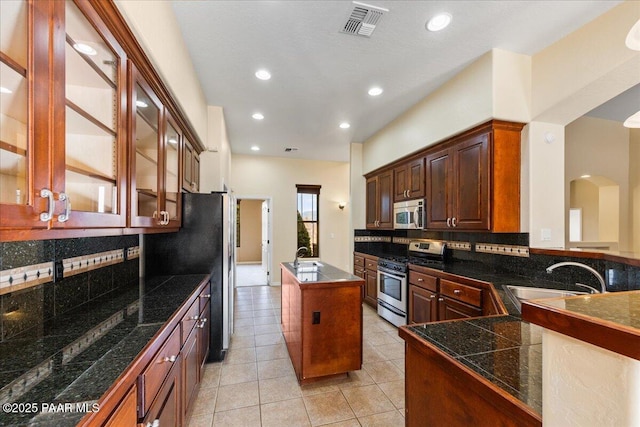 kitchen featuring stainless steel appliances, a center island, sink, and backsplash