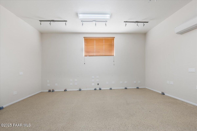 unfurnished room featuring track lighting and an AC wall unit