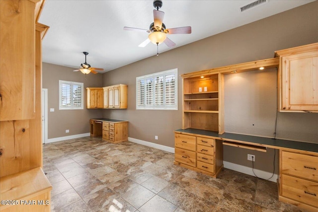 unfurnished office featuring built in desk and ceiling fan