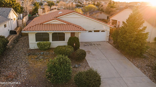 mediterranean / spanish home with stucco siding, a tiled roof, concrete driveway, and a garage