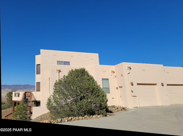 10614 E High Point Dr, Dewey-Humboldt, AZ 86327 - view of front facade with stucco siding, concrete driveway, a mountain view, and a garage