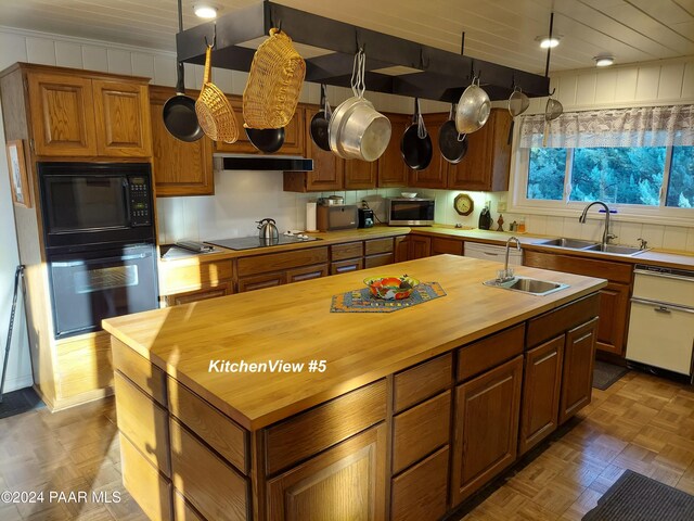 kitchen with butcher block countertops, sink, light parquet flooring, and black appliances