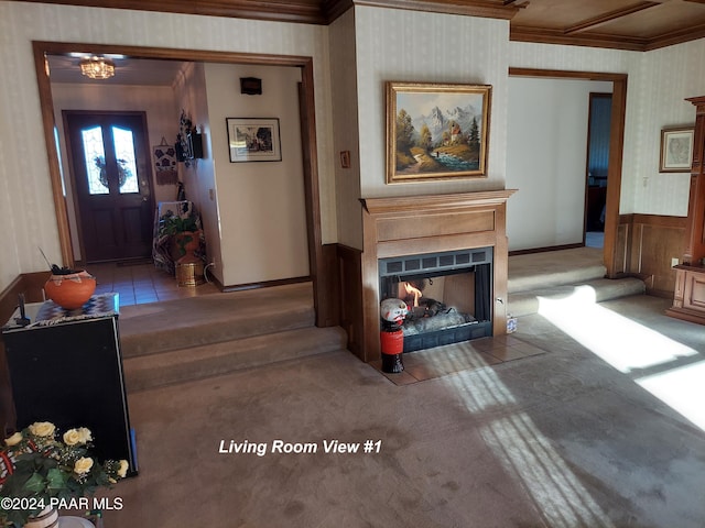 living room with wallpapered walls, baseboards, a fireplace with flush hearth, crown molding, and carpet floors