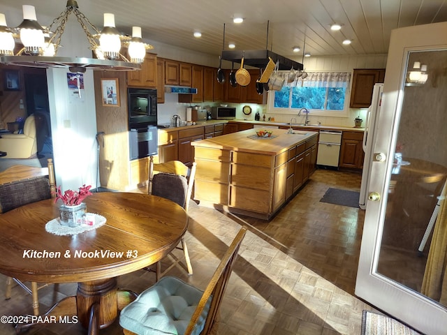kitchen featuring wooden counters, an inviting chandelier, a kitchen island, a sink, and black appliances