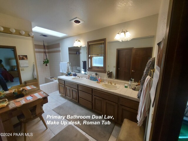 bathroom featuring a bathtub, vanity, tile patterned floors, a skylight, and a notable chandelier