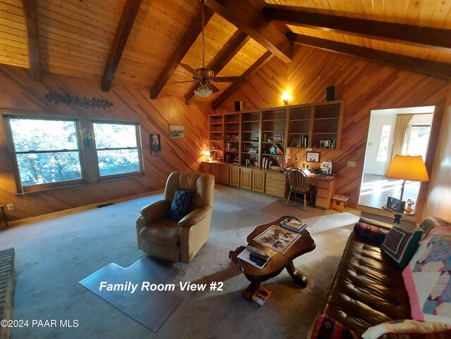 living room with wood walls, ceiling fan, a healthy amount of sunlight, and beam ceiling