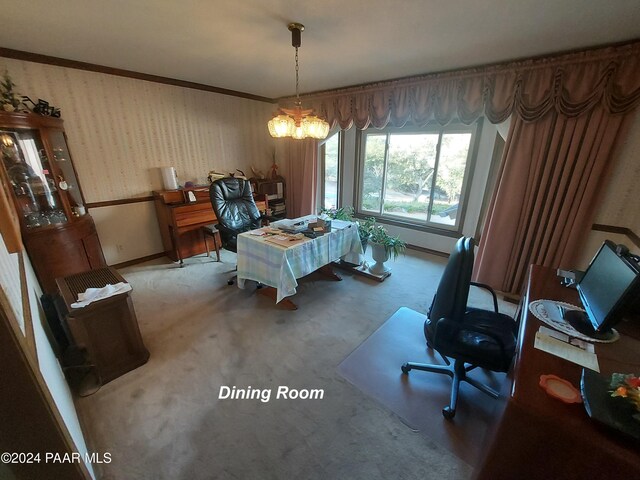 dining space with crown molding, carpet floors, and a notable chandelier