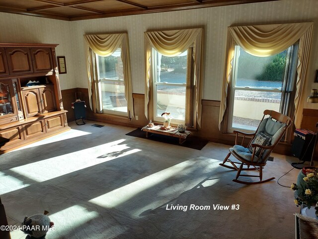 sitting room featuring light colored carpet, coffered ceiling, and wood walls