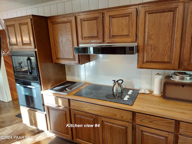 kitchen with light hardwood / wood-style floors, extractor fan, and black appliances