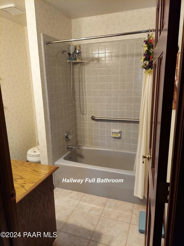 bathroom with toilet, shower / bath combination with curtain, and tile patterned floors