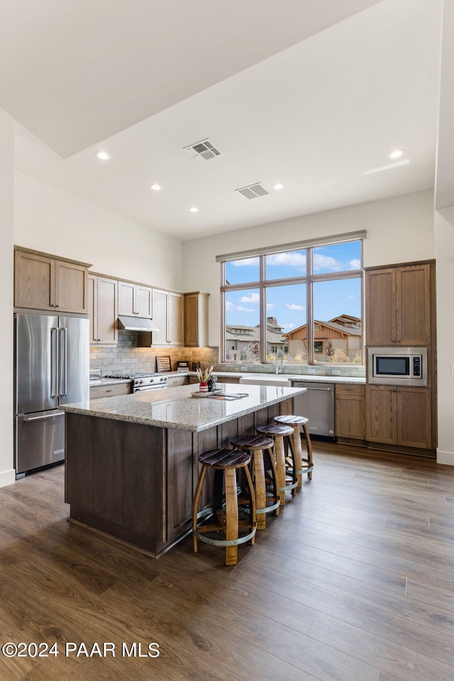 kitchen featuring dark hardwood / wood-style flooring, a kitchen island, high end appliances, and light stone counters